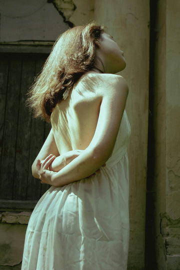 a person in a white dress kissing a wall