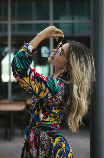 a woman in a colorful dress leaning against a pole