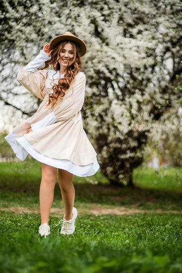 A woman in a dress and hat standing in the grass
