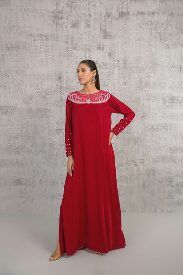 A woman in a long red dress standing in front of a wall