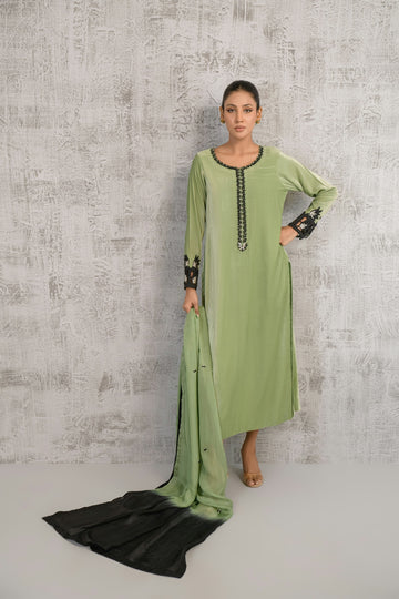 A woman standing in front of a wall wearing a green dress