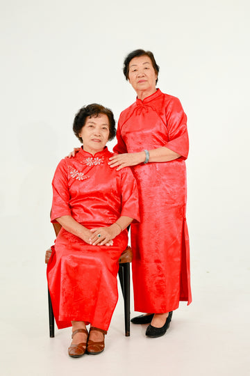 Two elderly asian women in red dresses.