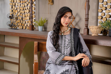 A woman in a gray outfit with black accents sits.