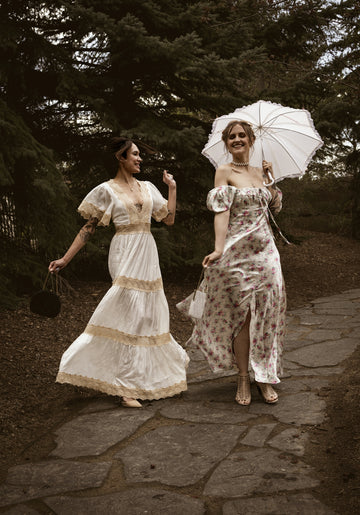 Two women in vintage dresses walking on a path