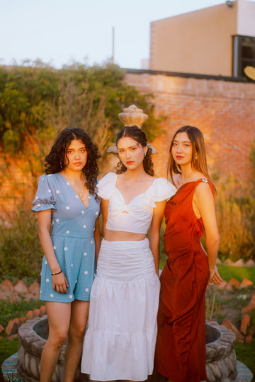 Three young women posing outdoors at sunset