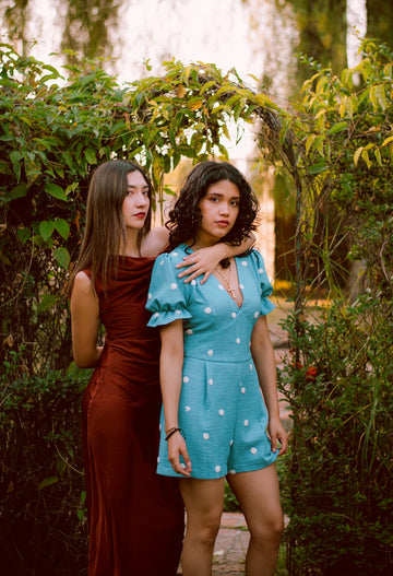 Two women in a garden under a leafy archway