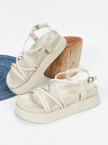 Black platform sandals with braided instep strap shown on foot and handheld for scale