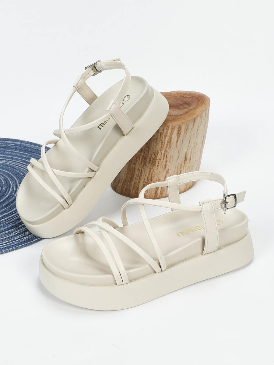 Black platform sandals with braided instep strap shown on foot and handheld for scale