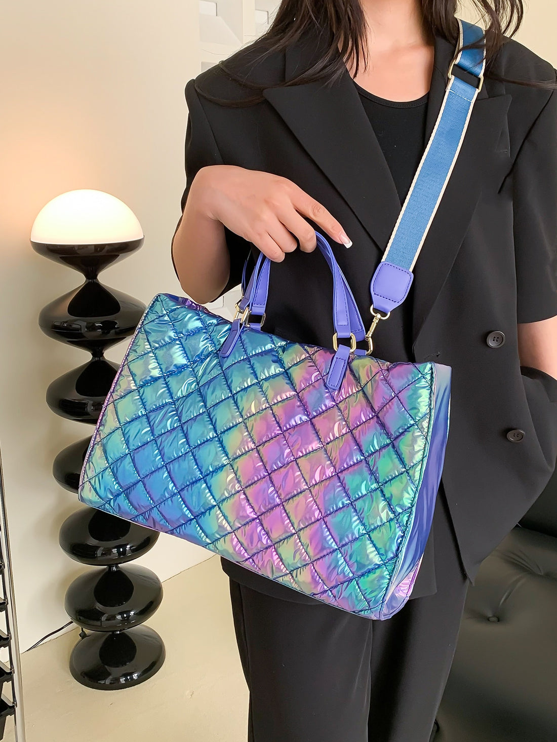 Catch the light and turn heads with this eye-catching holographic quilted top handle bag. The shimmering, iridescent finish shifts with every angle, making it the ultimate statement piece for anyone who loves bold style. Quilted detailing adds texture and dimension, while the sturdy top handle keeps your essentials secure and stylish. Whether you're heading to brunch, a night out, or just running errands, this bag brings that fun, futuristic vibe to any outfit. Compact yet spacious enough for your daily mus