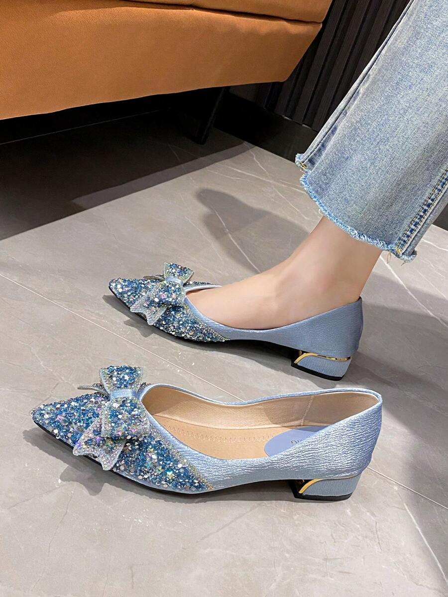Side view of blue crystal pointed-toe flats worn with cropped jeans