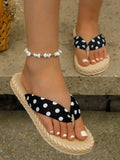 Front close-up of black and white polka-dot thong sandals on stone steps