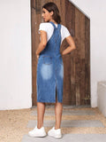Rear three-quarter view of blue denim pinafore dress showing patch pockets and split-back hem