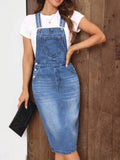 Close front view of blue denim overall dress with buckle straps, bib pocket, and side buttons