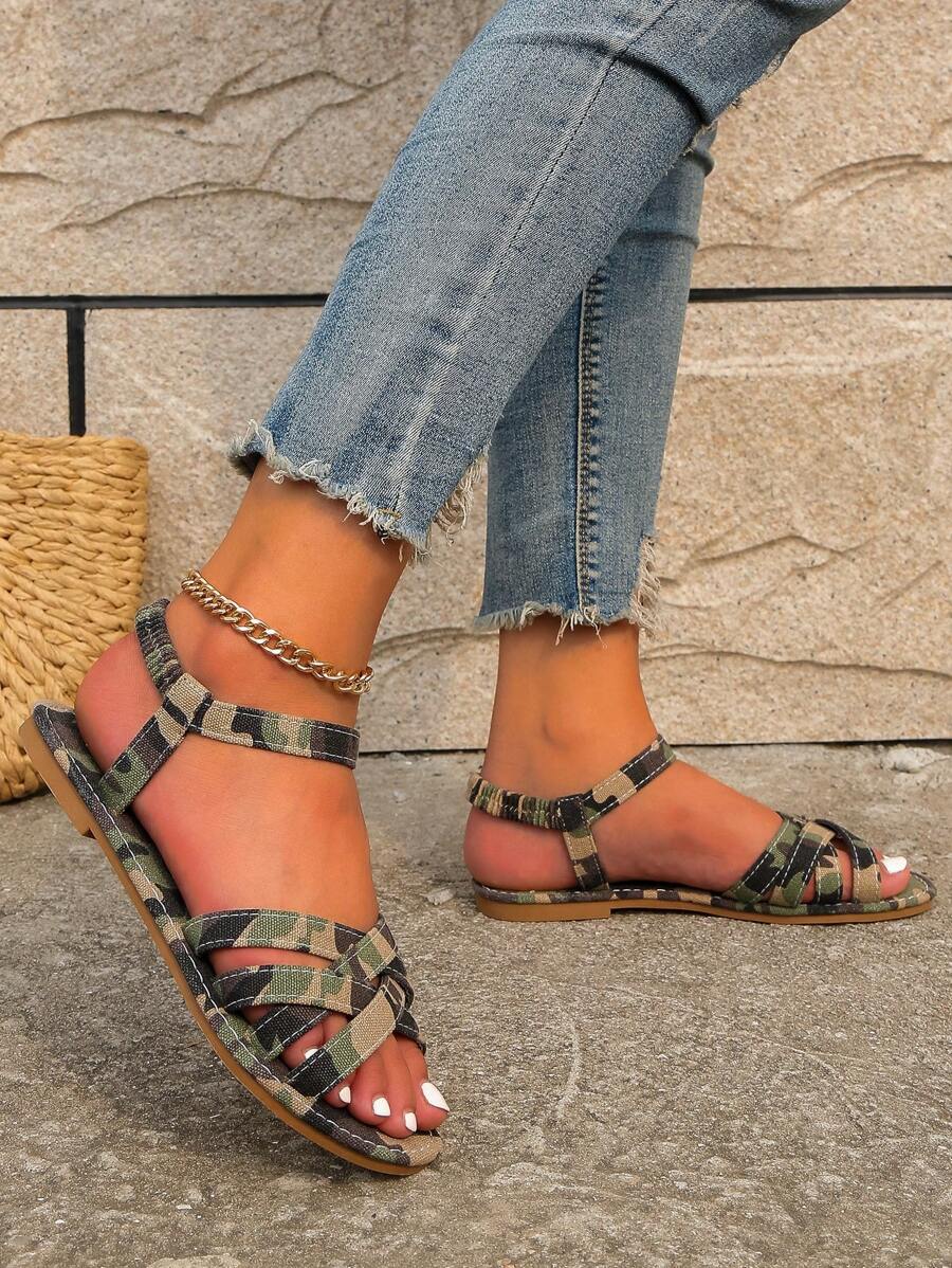 Top handheld view of camouflage interwoven flat sandals with one sandal worn outdoors