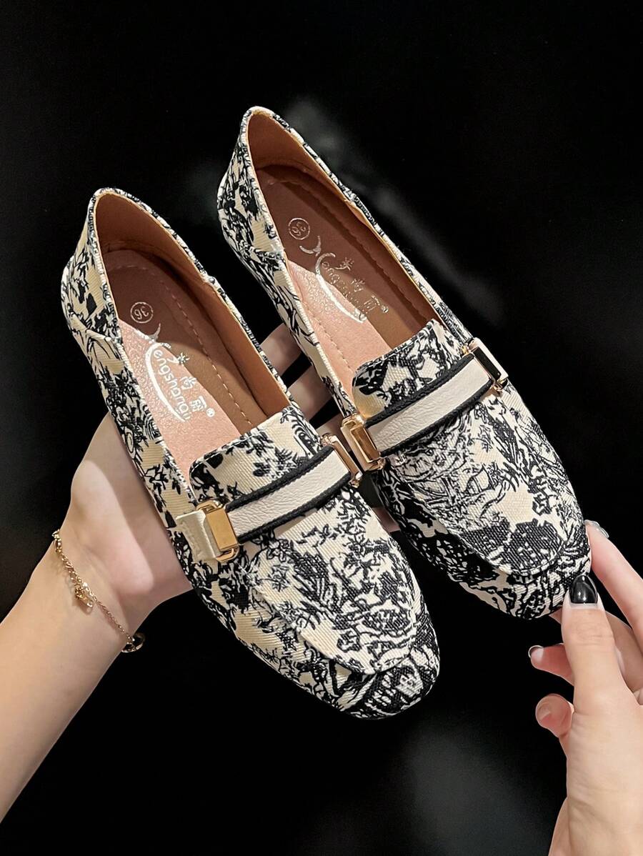 Close-up of cream printed loafer showing square-rounded toe and black trim