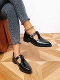 Solid black patent-look Mary Jane pumps worn with jeans in an angled floor view