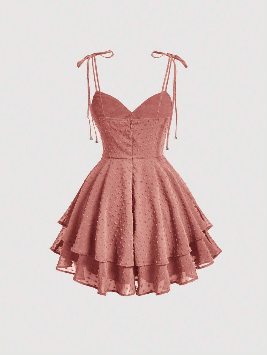 Elevate your wardrobe with this charming Swiss Dot Tie Shoulder Cami Dress. Featuring delicate spaghetti straps, a flattering ruched bust, and a distinctive two-layer tiered hem, this piece effortlessly transitions from casual outings to special occasions. The high-waist silhouette and knot detail at the shoulders add sophisticated touches, while the short length keeps things breezy and modern. Crafted from 100% polyester woven fabric in a rich redwood tone, it's perfect for graduation season