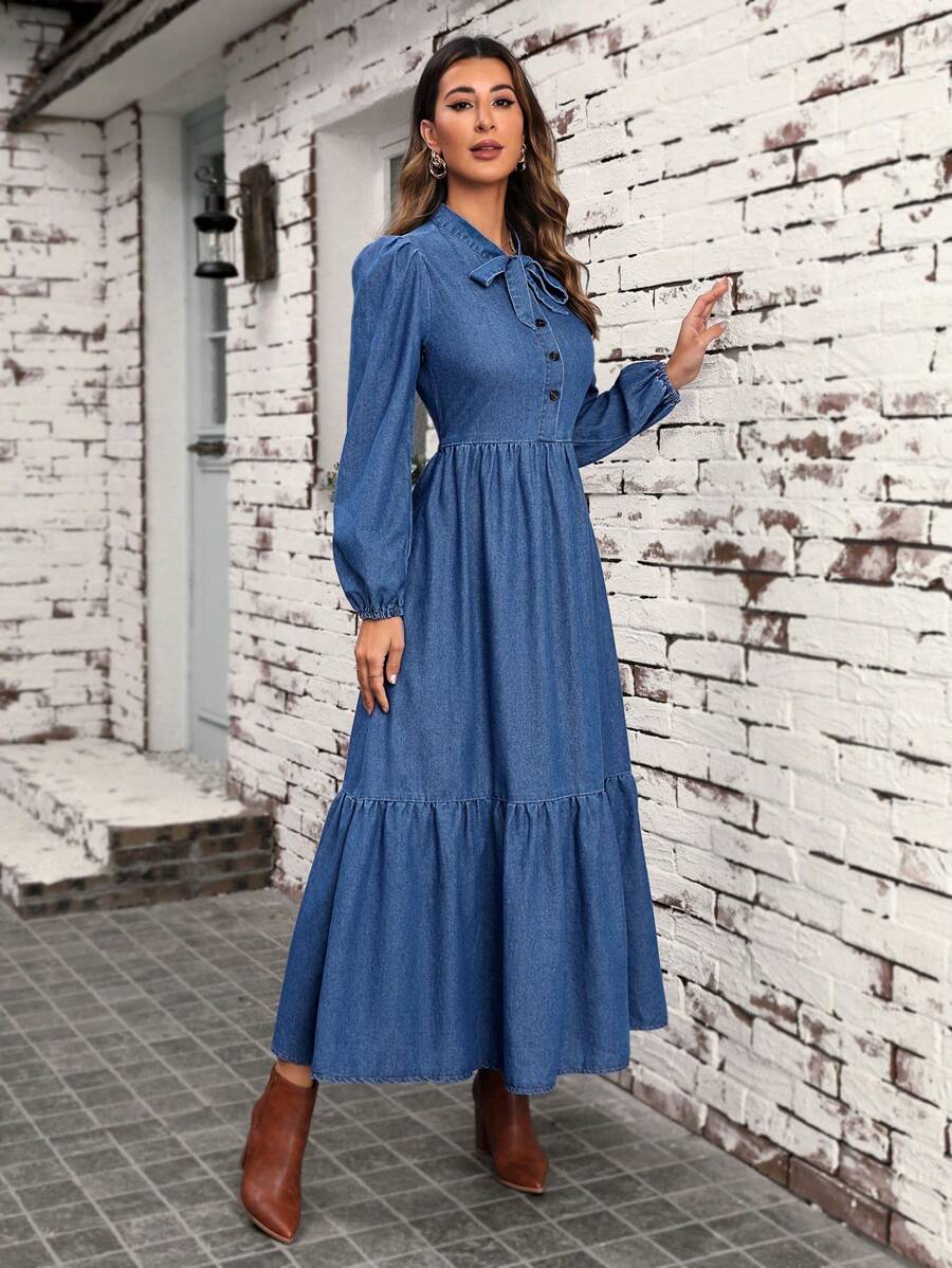 Angled view of denim bow neck dress with button front and ruffle hem