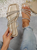Gold glitter flat slide sandals with rhinestone straps and black outsole