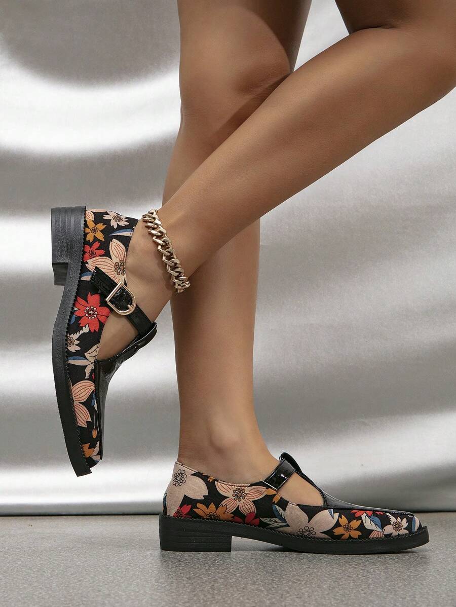 Side profile of floral print T-strap pumps with low block heels and stitched soles