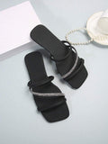 Angled view of black open toe slide sandals with padded tube straps