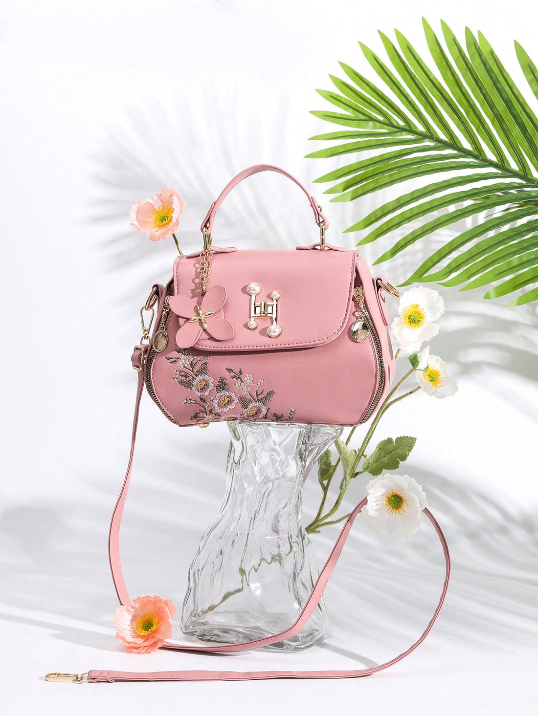 Expertly crafted with a chic floral embroidered design and a minimalist silhouette, this crossbody bag is a stylish and functional accessory. Its turn lock design adds a touch of sophistication while keeping your belongings secure. Elevate your everyday look with this must-have handbag.