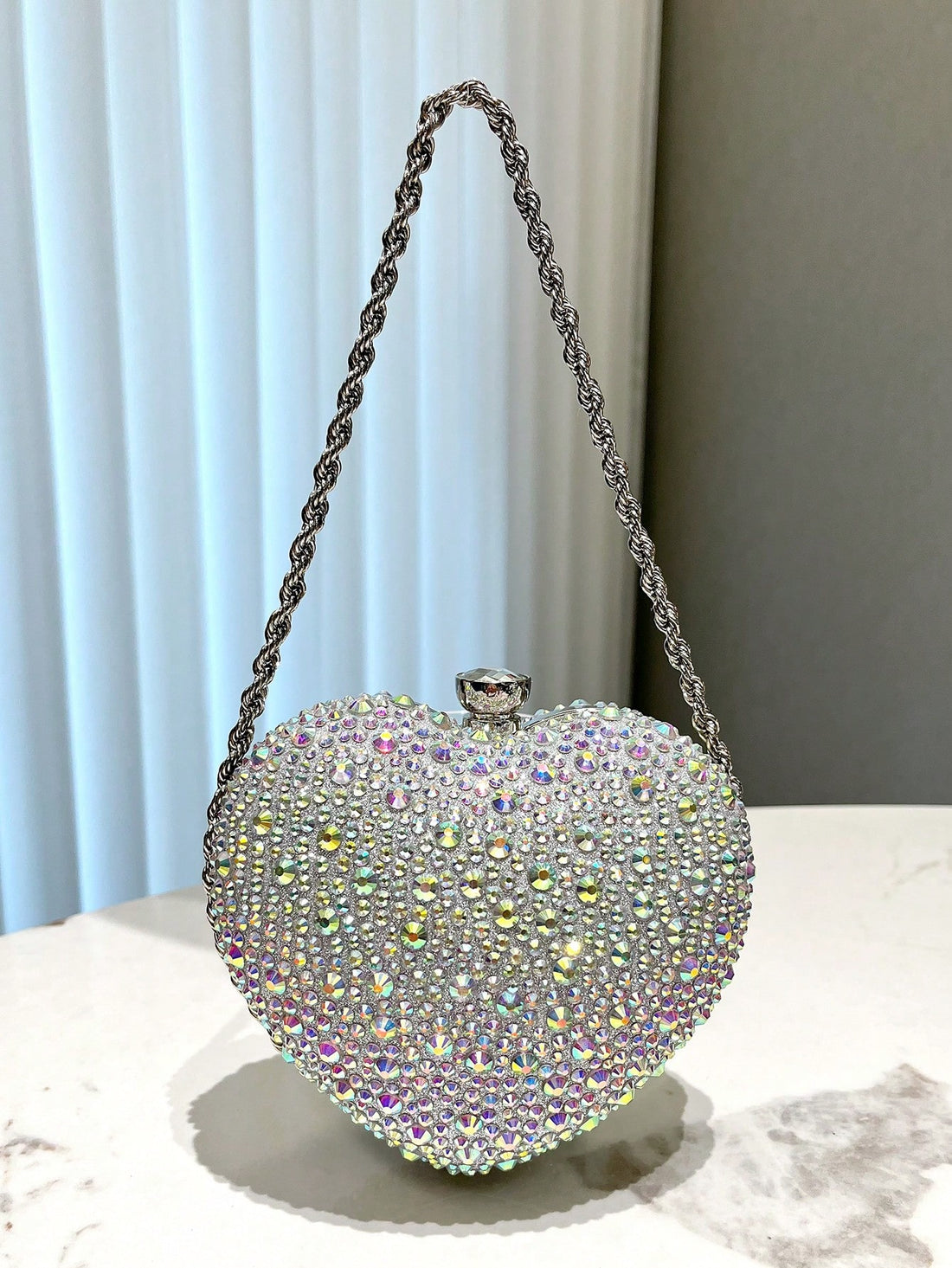 Add a touch of elegance to any special occasion with our Dazzling Diamond Heart Evening Bag. Perfect for parties, weddings, and more, this stunning bag is sure to make a statement. Its intricate design and sparkling diamonds will have you dazzling all night long. Elevate your style with this must-have accessory.