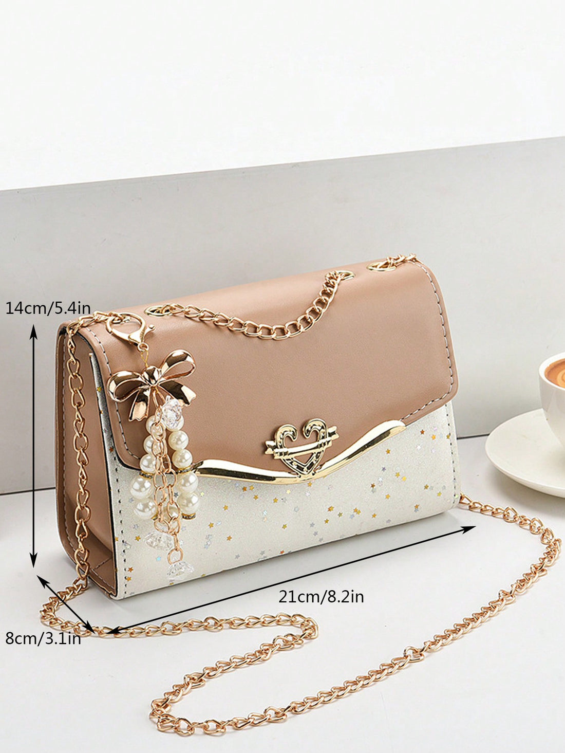This small shoulder bag features a chic two-tone design with faux pearl accents, adding a touch of sophistication to any outfit. The compact size is perfect for keeping your essentials within reach while on-the-go. Add a classy touch to your wardrobe with this elegant bag.
