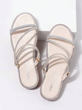 Top view of beige flat sandals with crisscross rhinestone straps and gold loop hardware