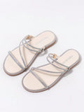 Angled view of nude rhinestone slide sandals with toe strap and diagonal straps
