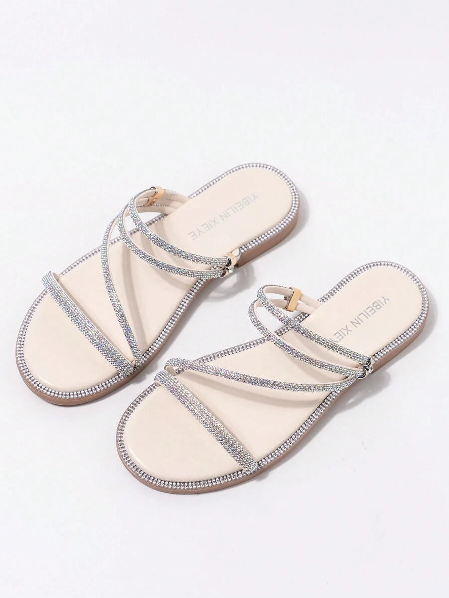 Angled view of nude rhinestone slide sandals with toe strap and diagonal straps