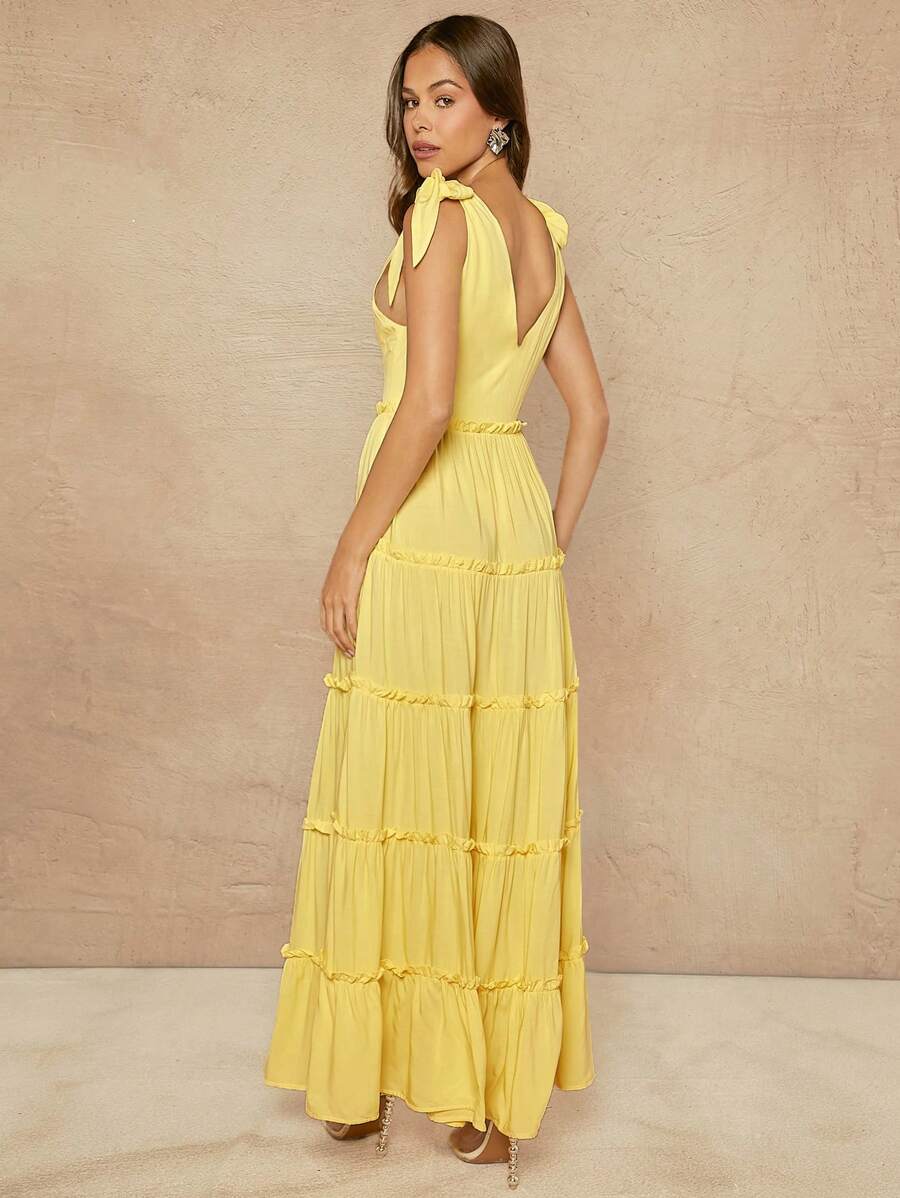 Step into summer fun with this playful maxi dress featuring tiered frills and charming tie straps. Easy-to-wear buttons add a touch of whimsy while offering a comfortable fit. Perfect for sunny days and breezy evenings, this dress brings effortless style with a flirtatious flair.