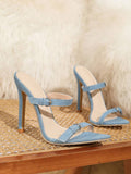 Pair of light blue denim pointed toe stiletto mule sandals on woven chair