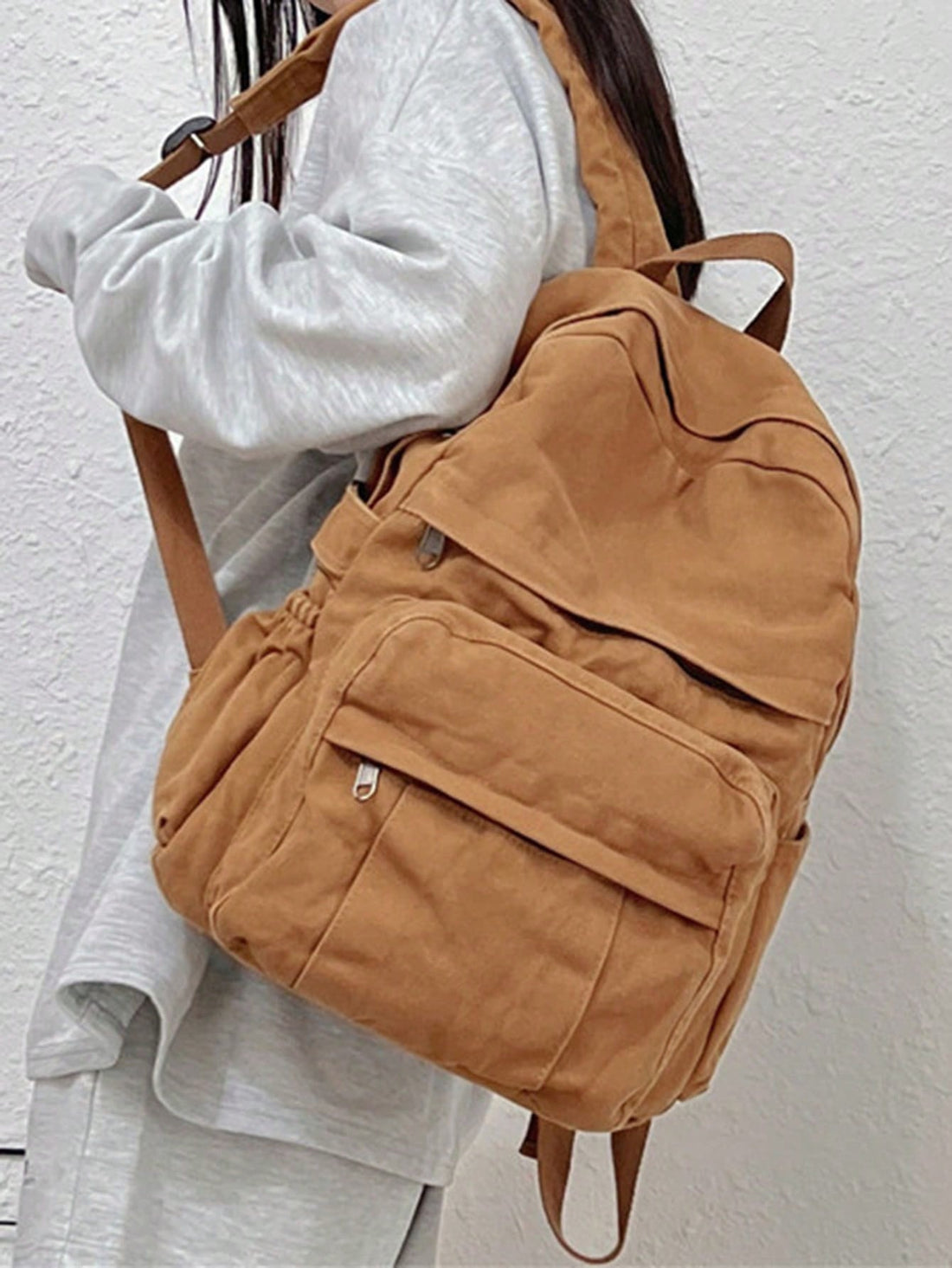 A blue denim canvas backpack with double shoulder straps, displayed against a simple background, with a purple strap visible.