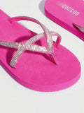 Oblique close-up of hot pink jeweled thong flip flops in studio light