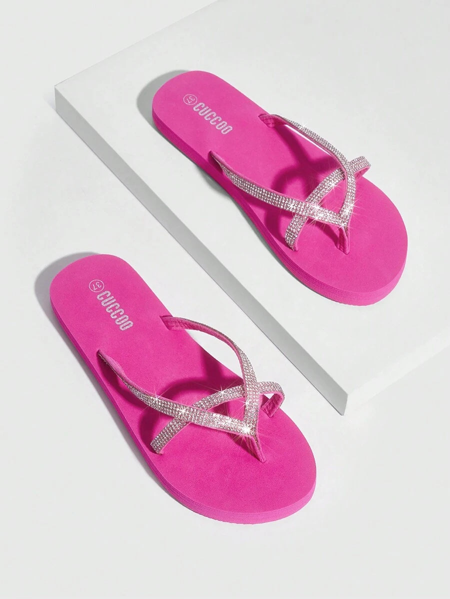 Overhead product view of hot pink rhinestone flip flops on a white plinth