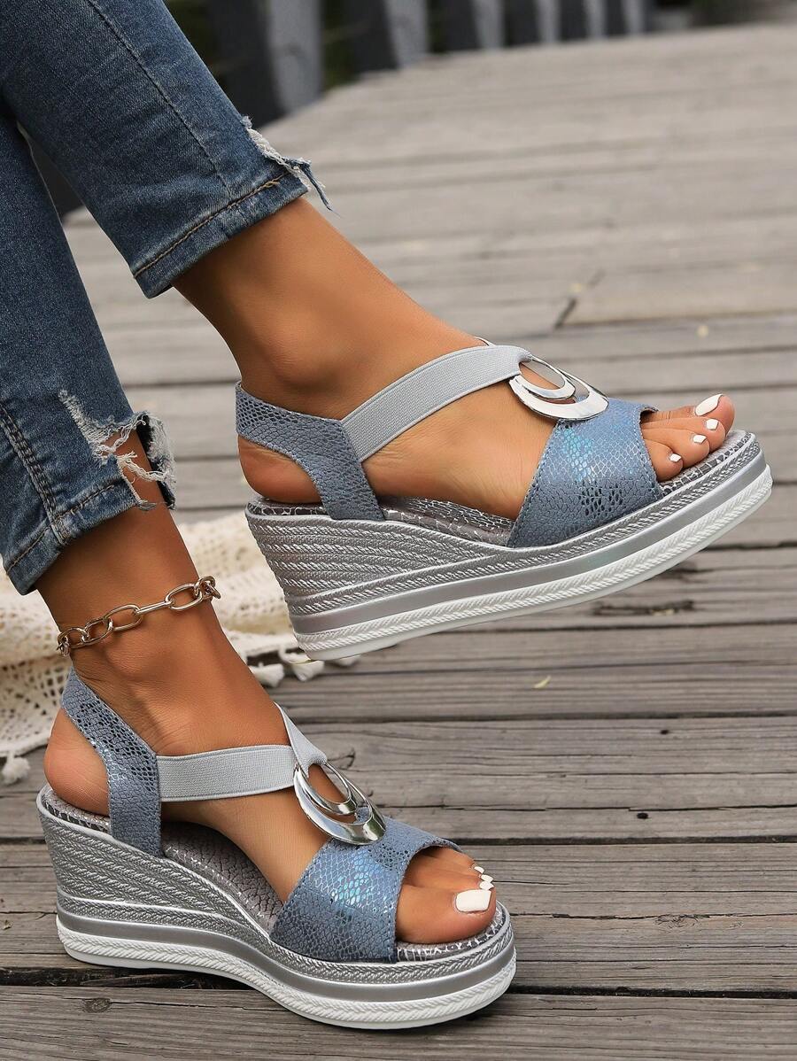 Side three-quarter view of metallic dusty blue open-toe wedge sandals worn with jeans