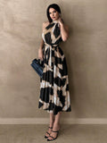 Front view of abstract print pleated halter midi dress with tie belt