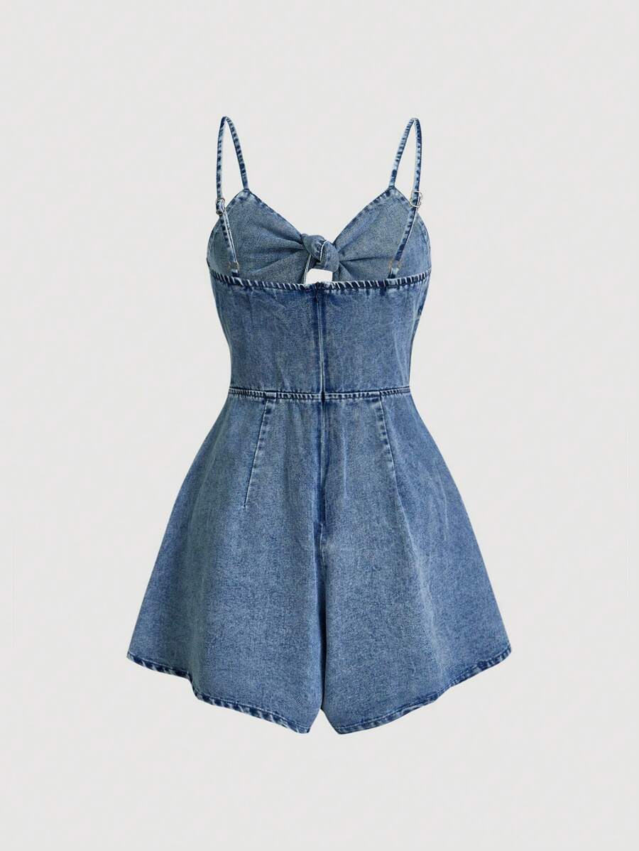 Front view of medium blue washed denim camisole romper with large bow and cutout
