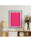 Framed pink motivational quote poster with orange typography in a room setting