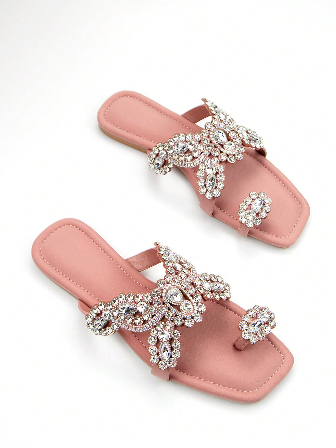 Elevate your party look with our Chic Floral Diamond Slip-On Mules. Featuring a stunning floral design with sparkling diamond accents, these elegant flat sandals are the perfect blend of style and comfort. Step out in style and make a statement at any occasion. Available in pink.