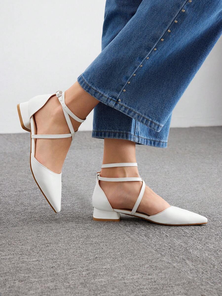 White pointed-toe criss-cross ankle strap pumps with low block heels worn with jeans