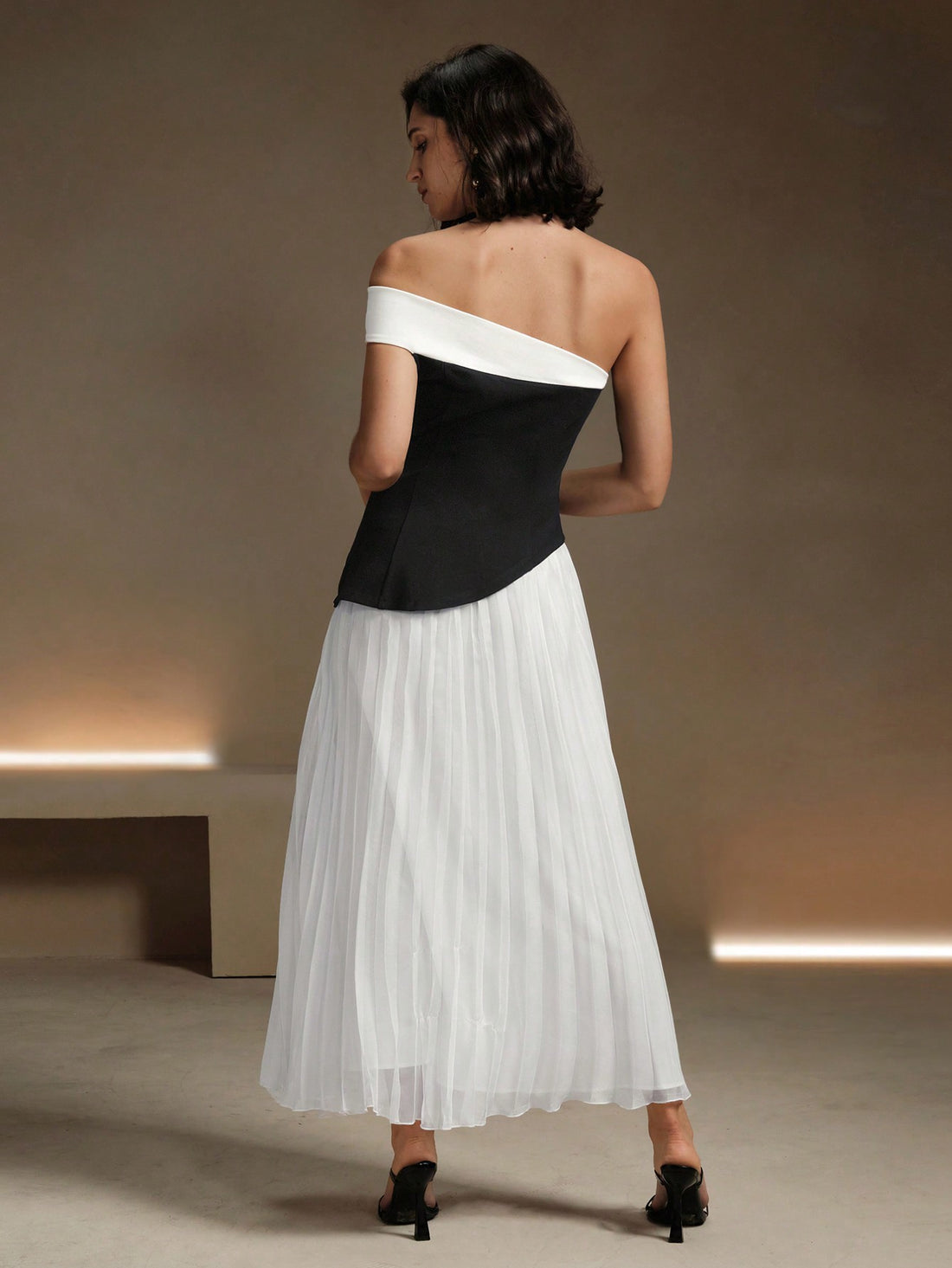 Slip into effortless elegance with this chic off-shoulder midi dress in classic black and white. The pleated detailing adds a touch of playfulness to this sophisticated look. Perfect for any occasion, this dress will make you stand out in style.