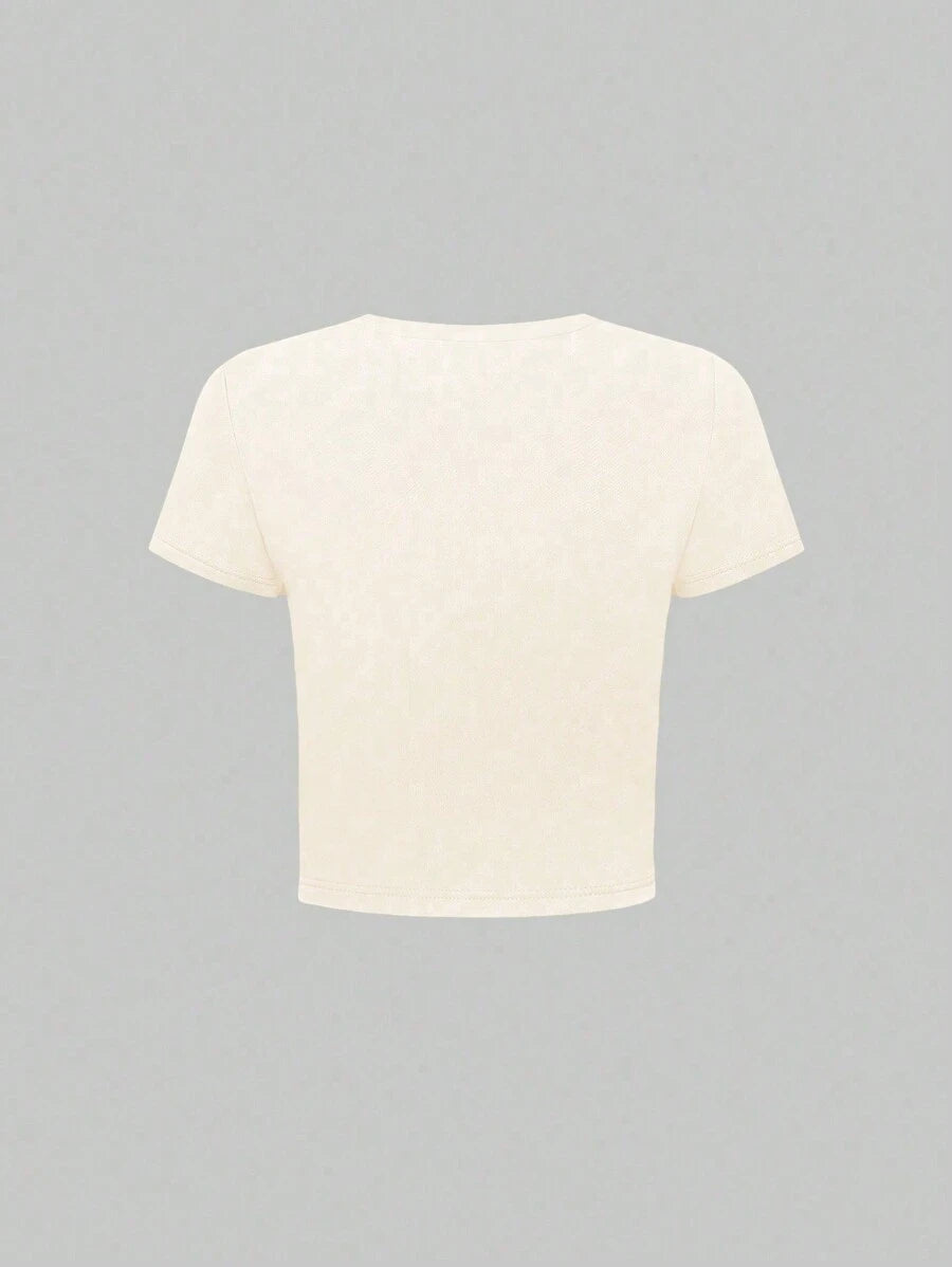 Front worn view of apricot cropped T-shirt with colorful marine-life graphic and jeans