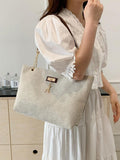 Beige large tote bag worn on shoulder showing front metal plaque gold deer charm and brown straps