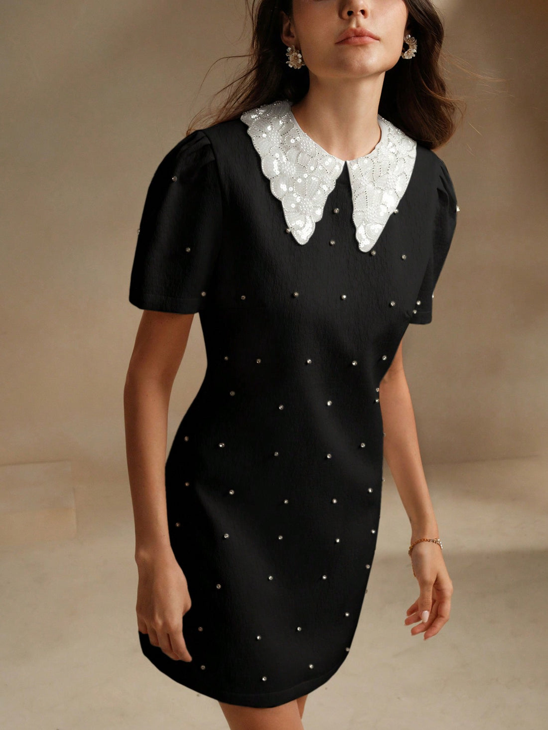 This mini dress is a nod to vintage style with its elegant design, pointy collar, and stunning crystal embellishments. Bring a touch of glamour to any occasion with this unique and playful piece. Perfect for those who love to stand out and make a statement with their fashion choices.