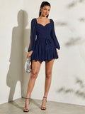 Navy wrap mini dress with sheer split puff sleeves tie waist ruffle hem and silver clutch