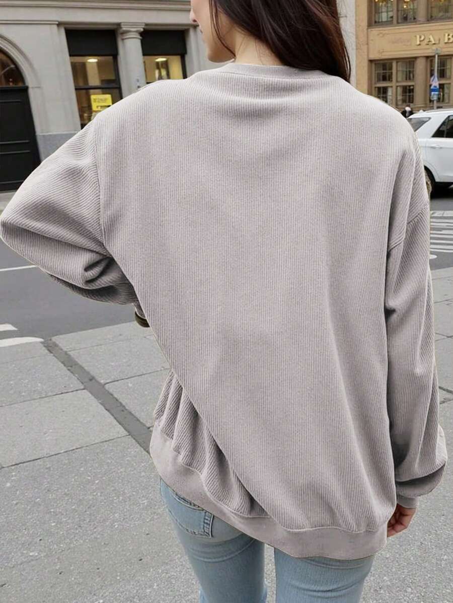 Front worn view of grey oversized crew-neck sweatshirt with leopard-print bow graphic