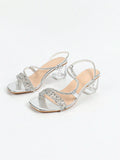 Angled view of silver party sandals with transparent heel and ankle buckle