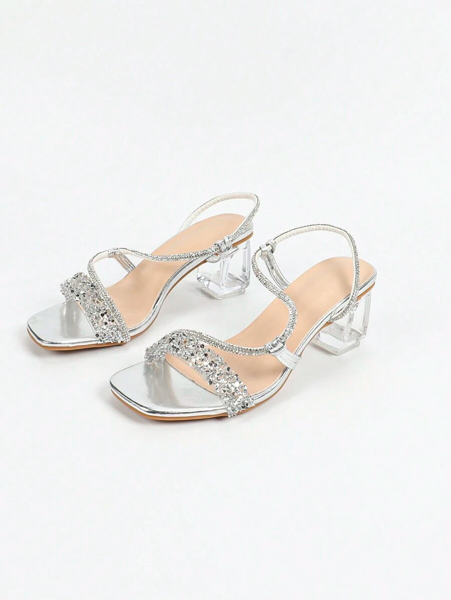 Angled view of silver party sandals with transparent heel and ankle buckle